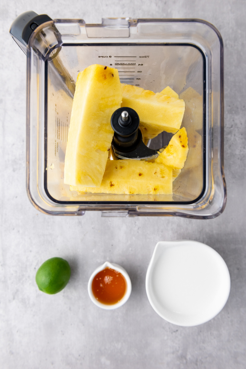Fresh pineapple chunks added to a blender for pineapple coconut lime popsicles.