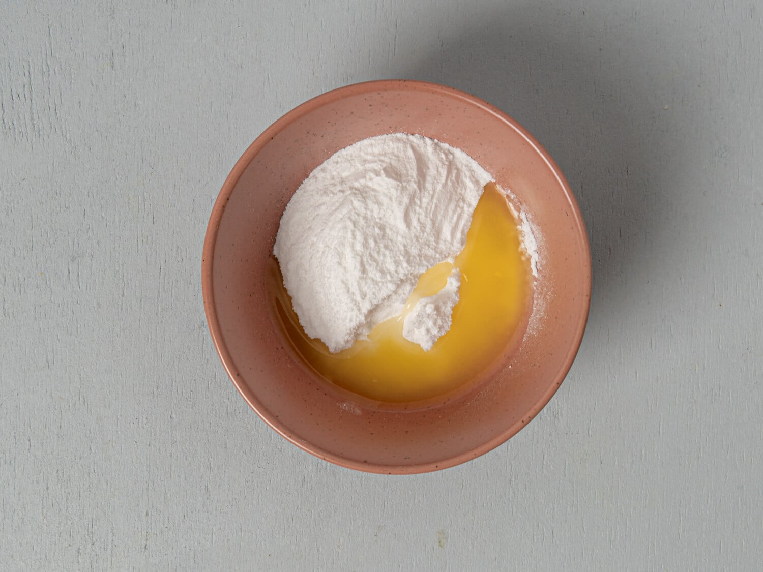 Powdered sugar and fresh orange juice being stirred together for orange scone glaze.
