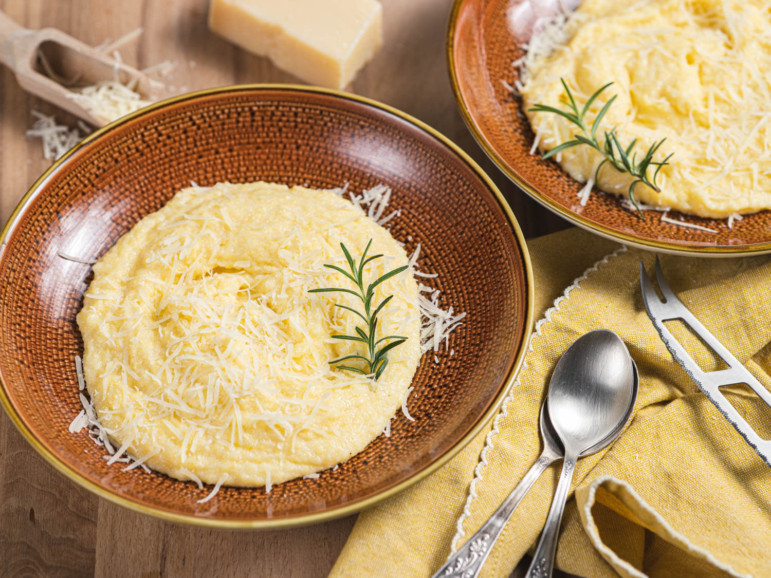 Fresh Parmesan cheese grated onto a plate for adding to creamy polenta.

