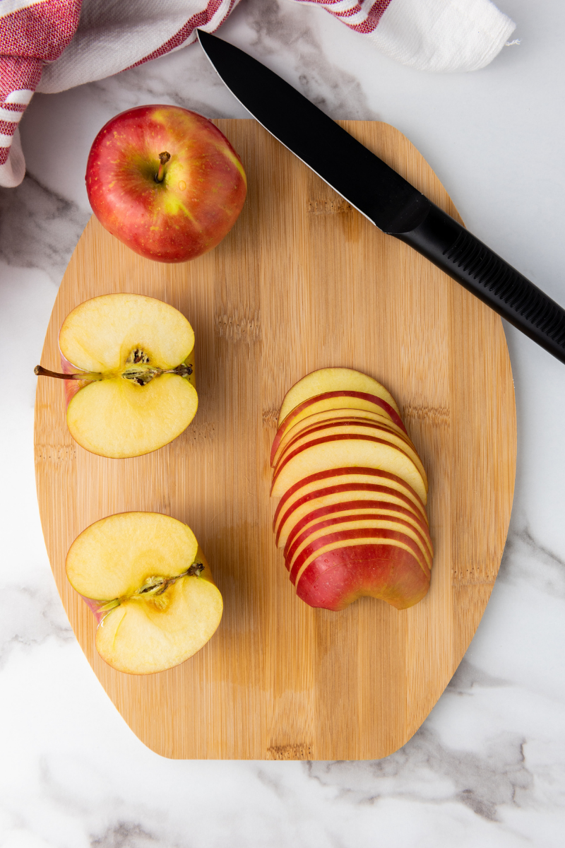 Thinly sliced red apples on a cutting board for making apple rose puff pastry.