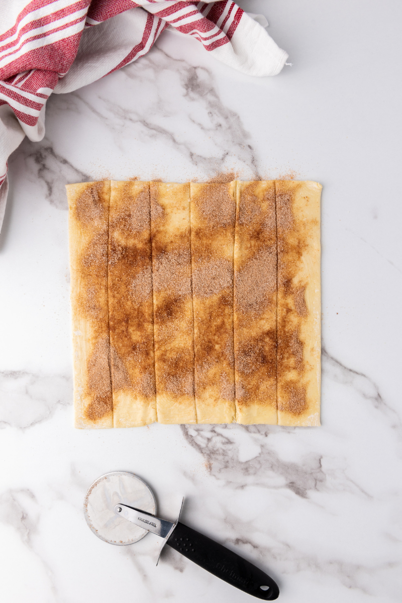 Puff pastry cut into strips with cinnamon sugar for homemade apple rose pastries.