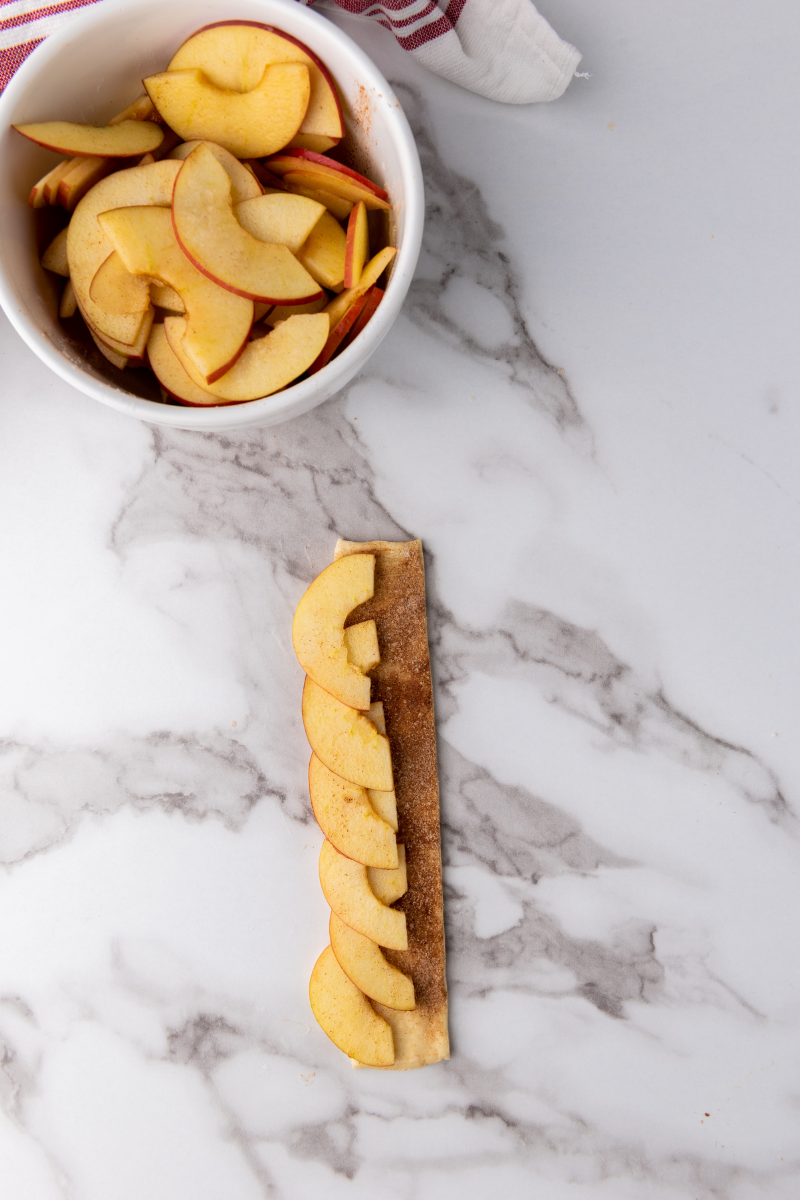 Thin apple slices layered along a puff pastry strip to form apple roses.