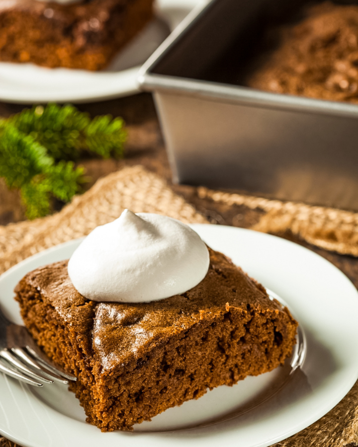 Delicious gingerbread cake topped with powdered sugar, showcasing warm spices and a moist texture, perfect for holiday gatherings.