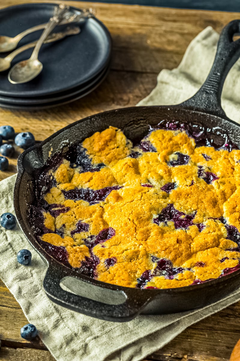 Easy blueberry cobbler baking in cast iron skillet with golden crust and bubbling blueberry filling