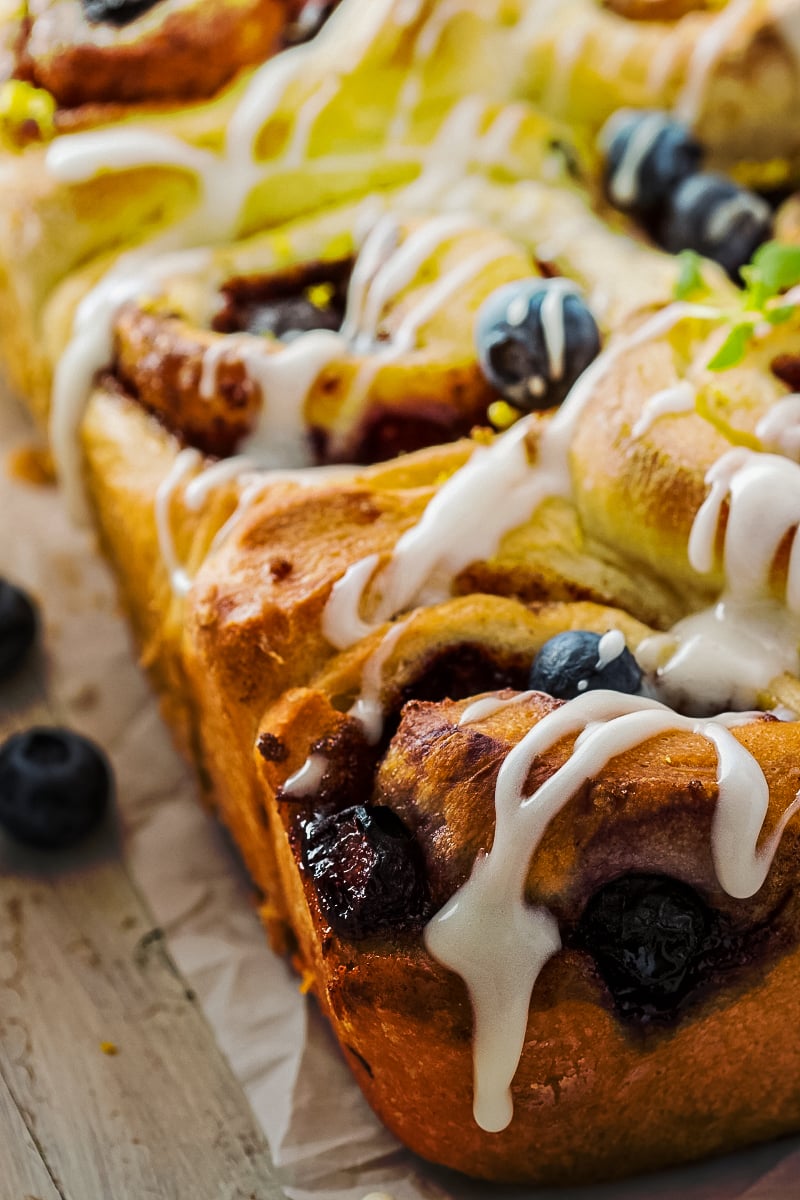 Golden-brown healthy cinnamon buns swirled with blueberry, lemon zest, and thyme, drizzled with fresh lemon glaze.