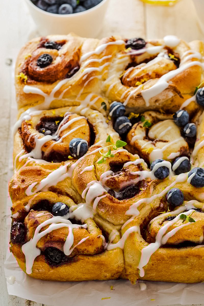 Golden-brown healthy cinnamon buns swirled with blueberry, lemon zest, and thyme, drizzled with fresh lemon glaze.