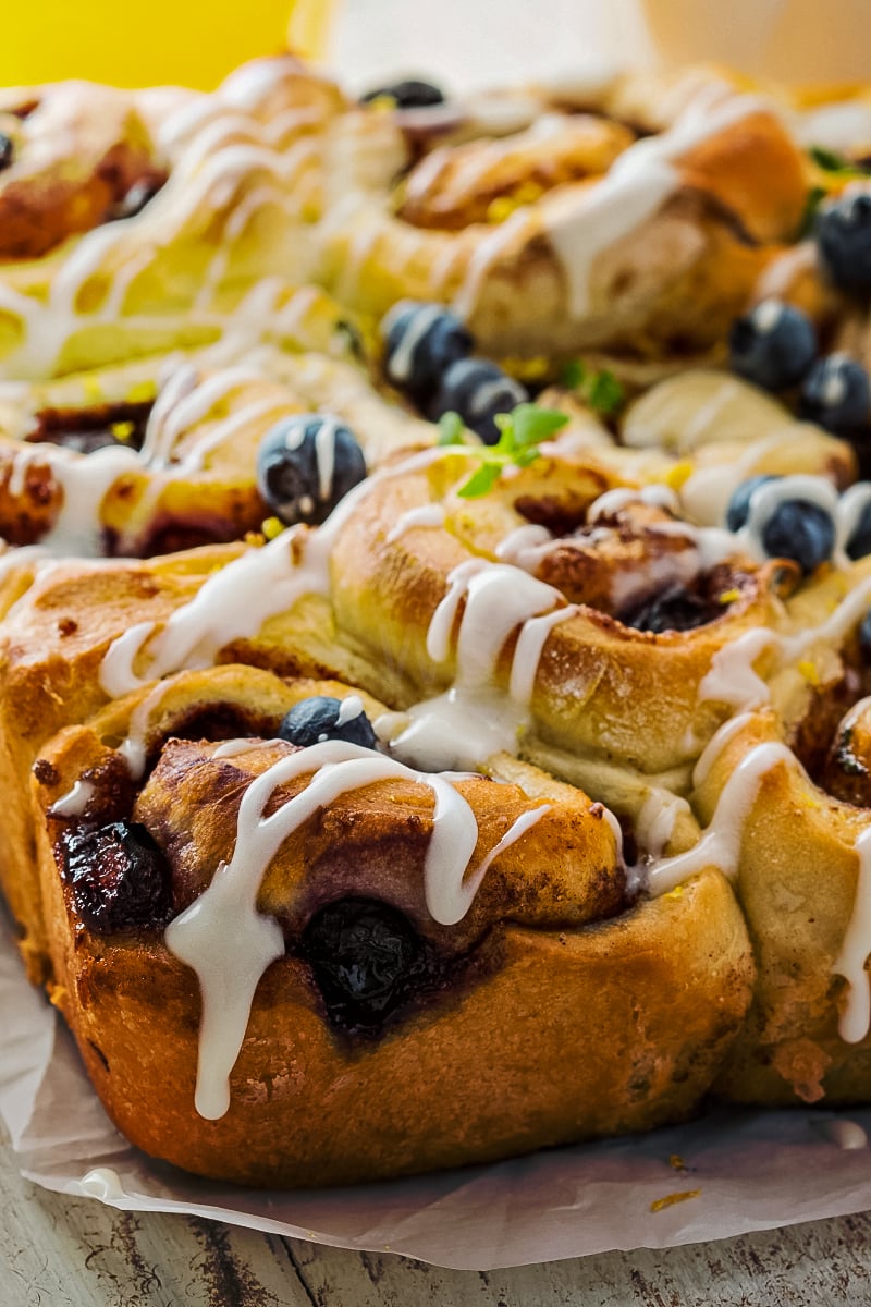 Golden-brown healthy cinnamon buns swirled with blueberry, lemon zest, and thyme, drizzled with fresh lemon glaze.
