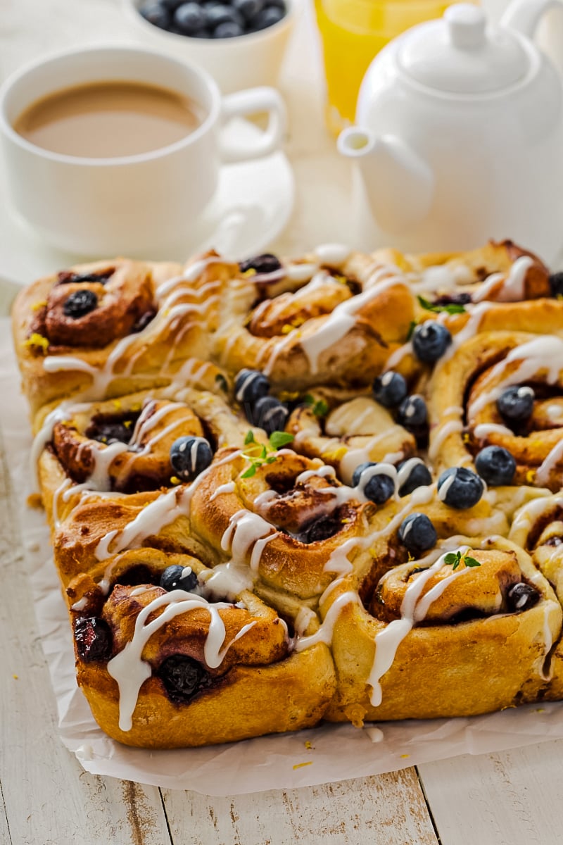 Golden-brown healthy cinnamon buns swirled with blueberry, lemon zest, and thyme, drizzled with fresh lemon glaze.