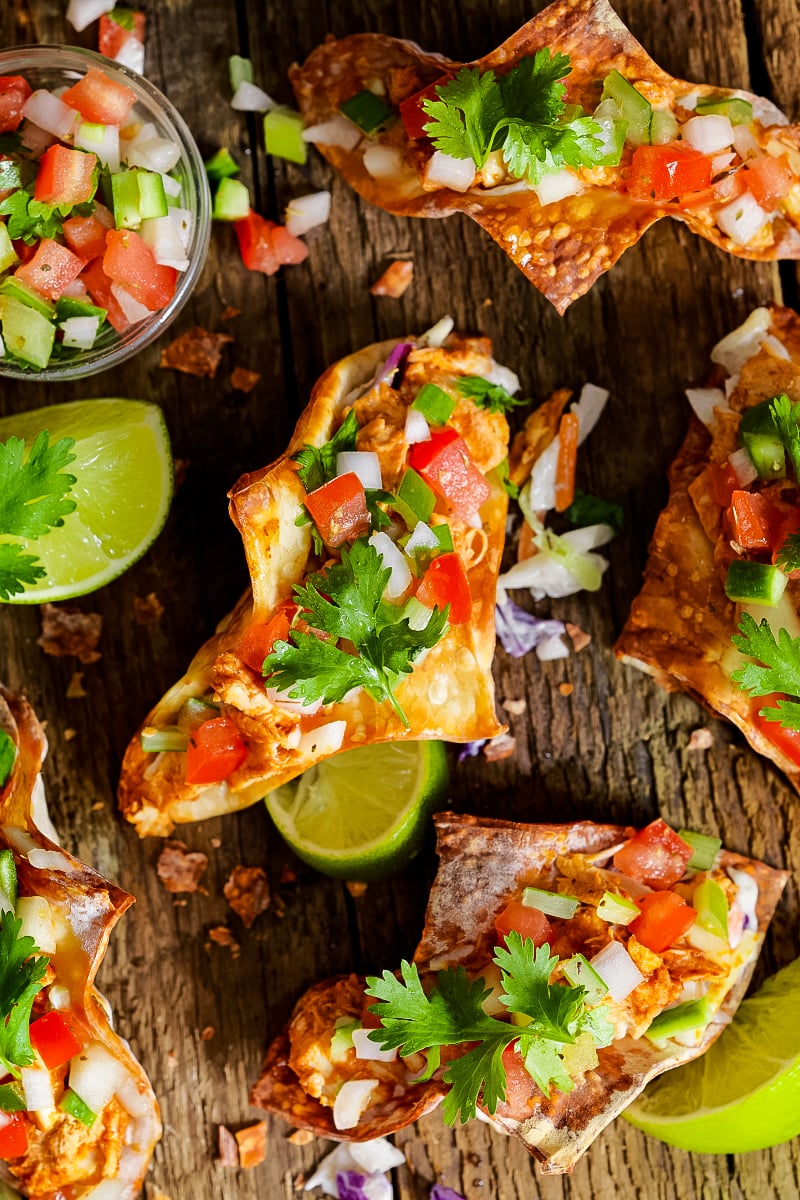 Crispy wonton tacos filled with spicy soy-ginger chicken, colorful Asian slaw, and drizzled sriracha mayo on a wooden platter."