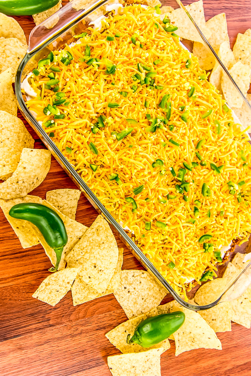 Layered Cheesy Jalapeño Bean Dip in a small casserole dish, showing beans, cheese, and jalapeños