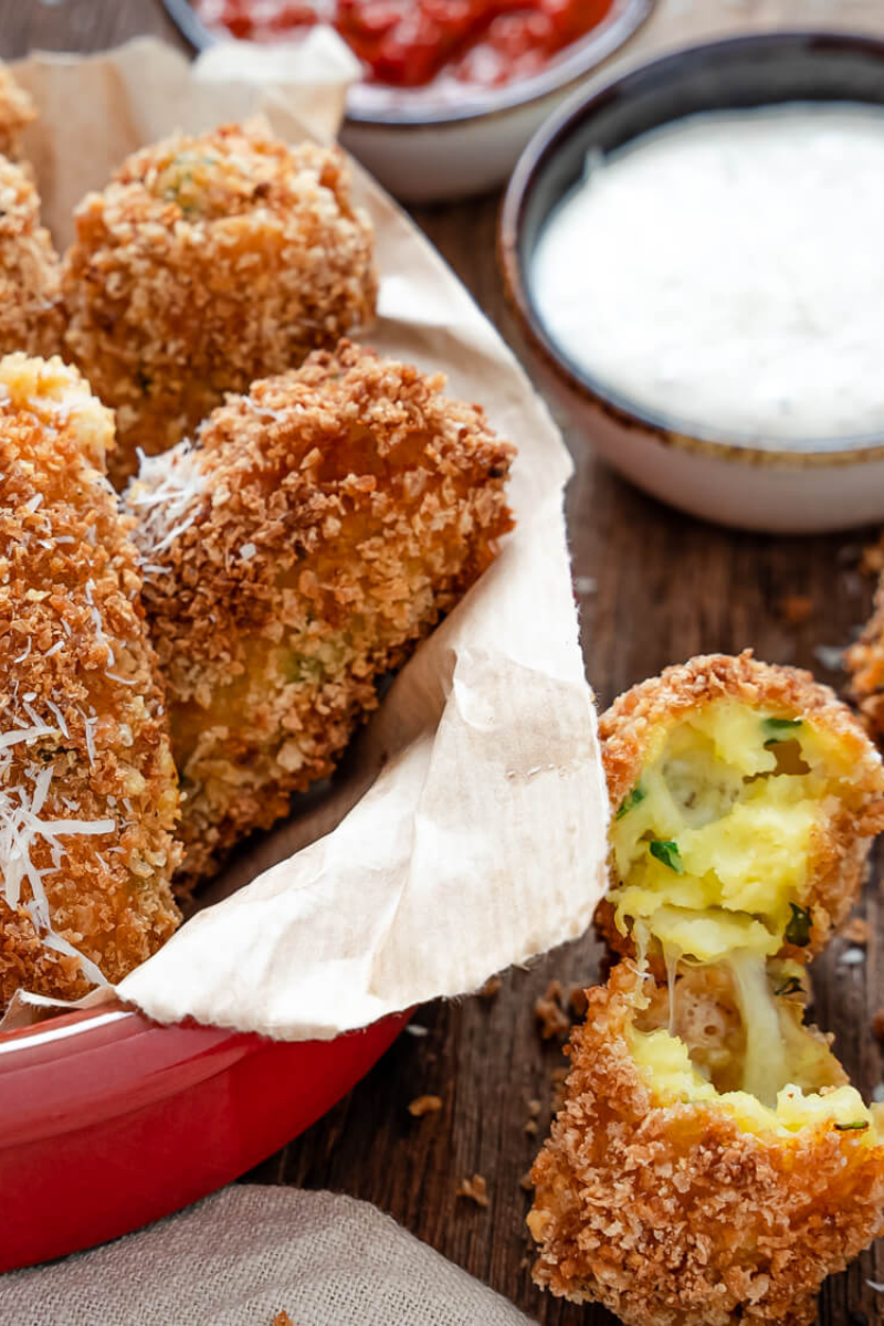 Golden brown mozzarella-stuffed potato croquettes served on a white plate with marinara sauce.