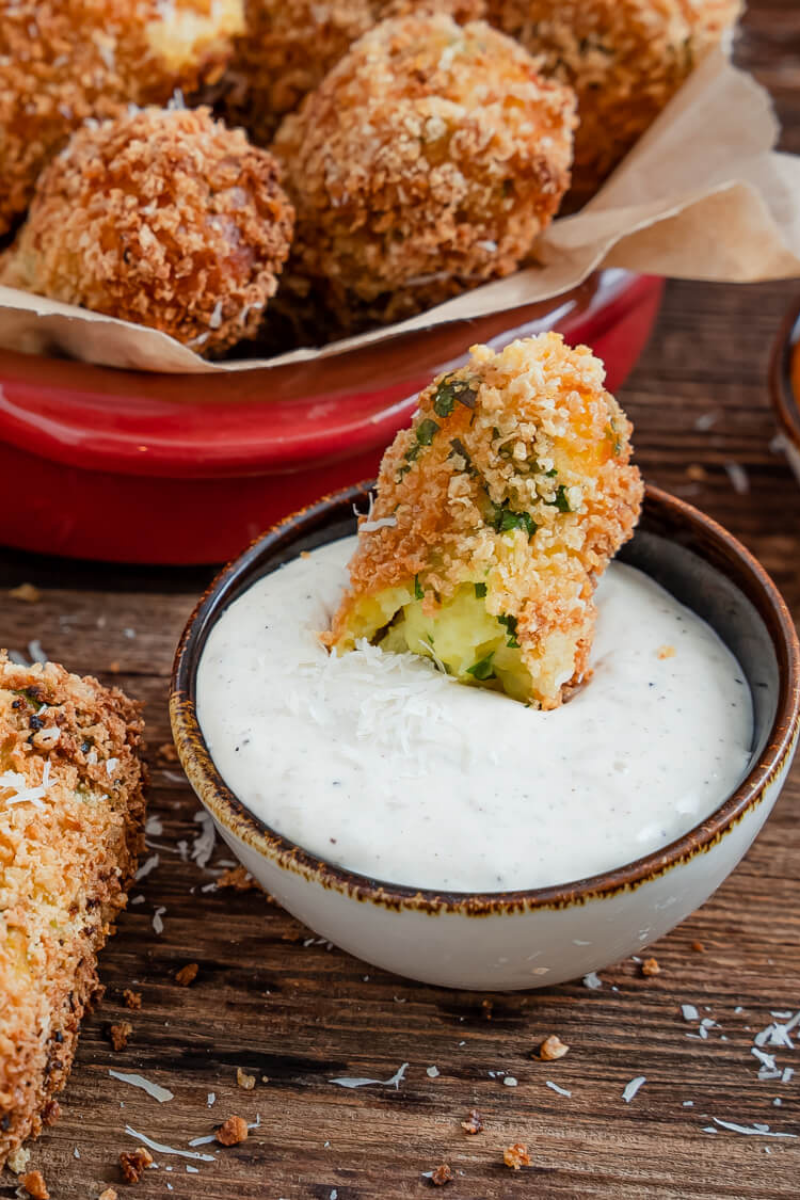 Golden brown mozzarella-stuffed potato croquettes served on a white plate with marinara sauce.