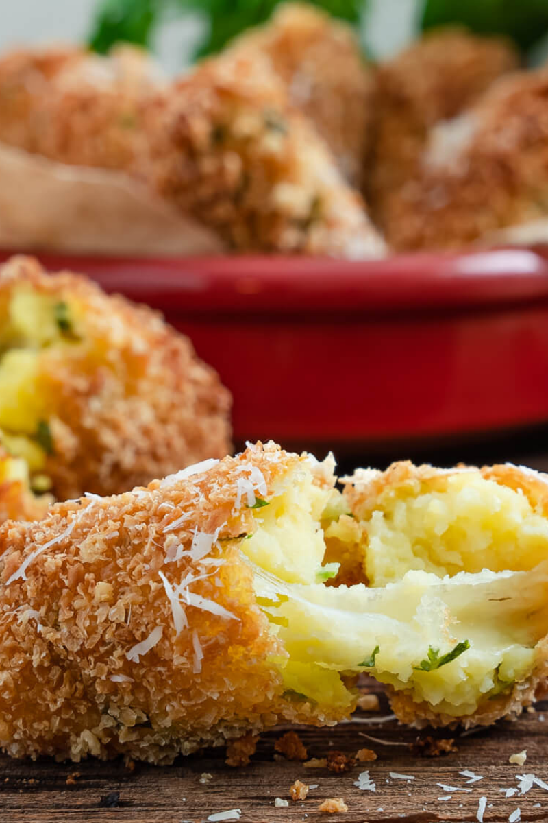Golden brown mozzarella-stuffed potato croquettes served on a white plate with marinara sauce.