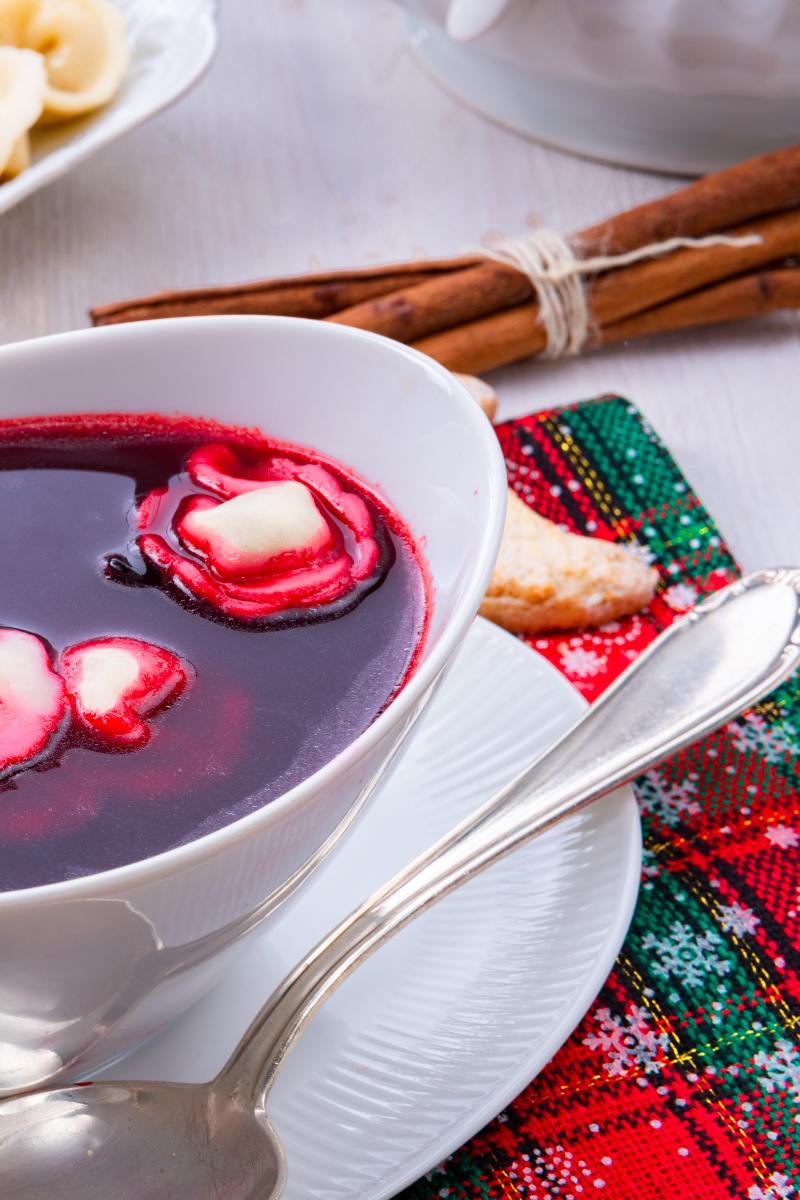 Bowl of red Polish barszcz soup with uszka dumplings and parsley garnish”