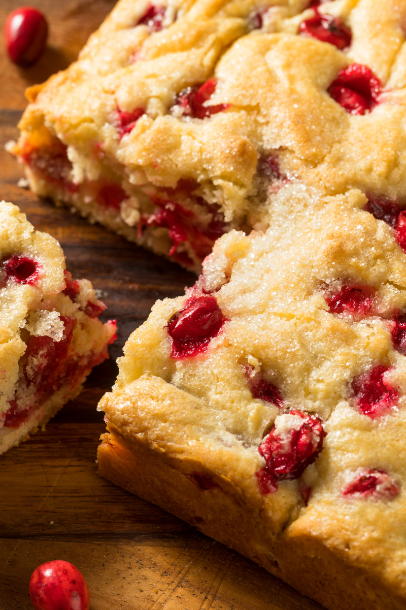 Homemade cranberry coffee cake in a square pan, topped with sugar and fresh cranberries.
