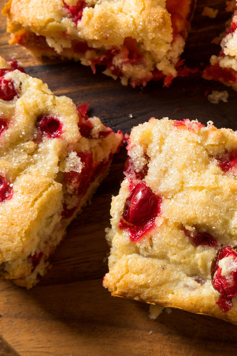Homemade cranberry coffee cake in a square pan, topped with sugar and fresh cranberries.