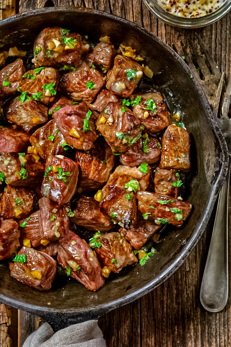 Golden seared steak bites tossed in garlic butter in a cast-iron pan