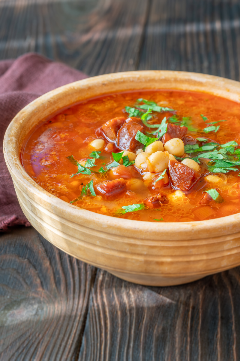 Creamy chickpea soup with spicy chorizo in a white bowl, topped with a sprinkle of paprika