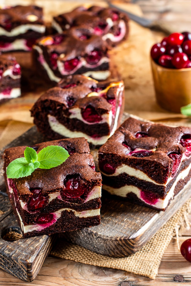Chocolate brownies with cottage cheese and cherries arranged on a rustic wooden board