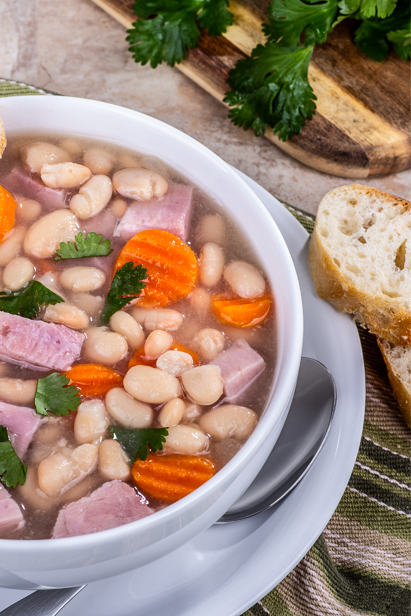 Close-up of white bean and ham soup in a bowl, featuring hearty beans, vegetables, and lean ham