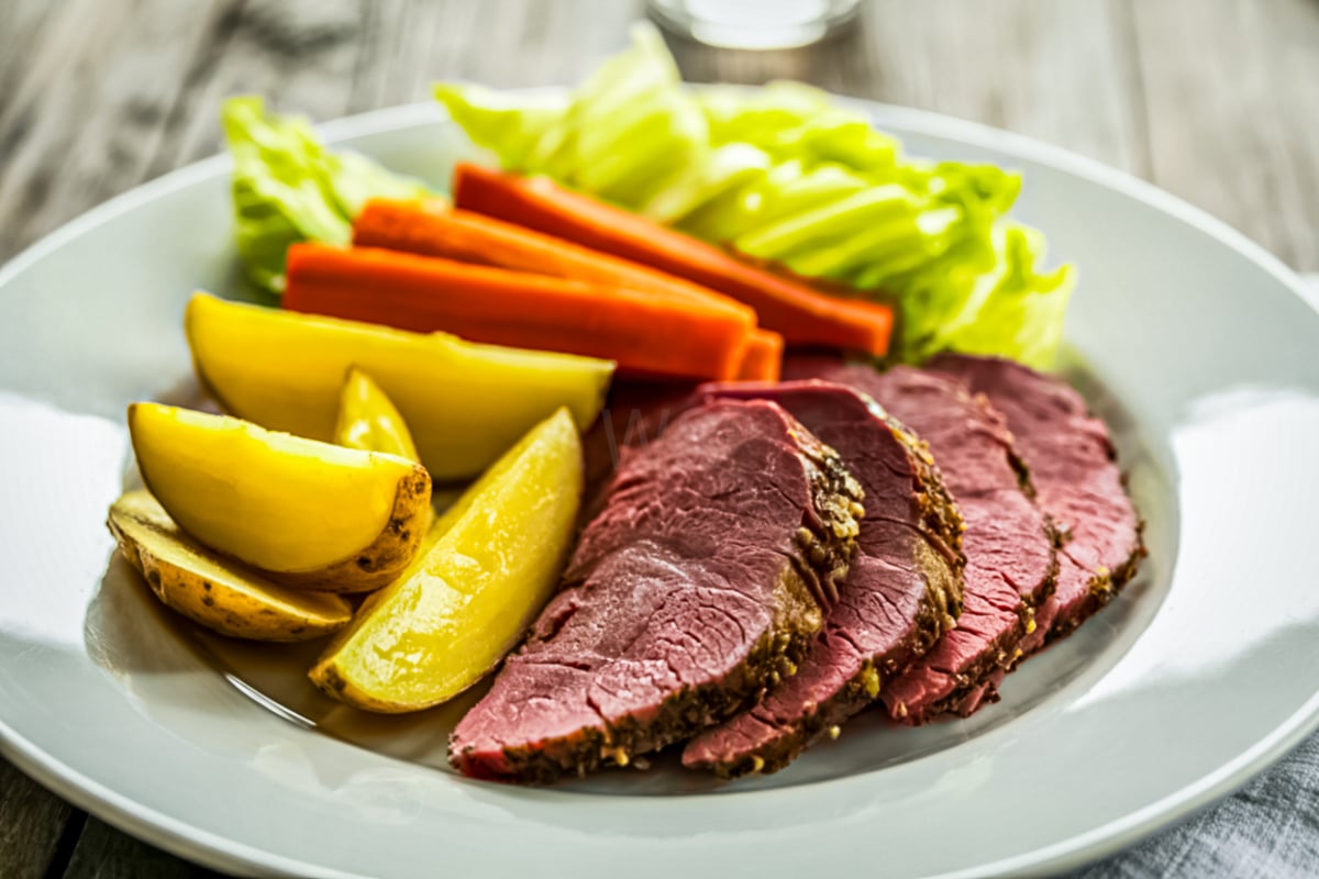 Sliced corned beef brisket with cabbage wedges and baby potatoes