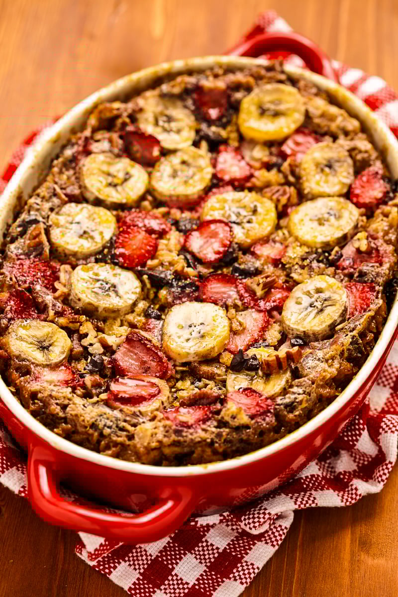 Baked strawberry banana oatmeal in an oval baking dish with sliced bananas and fresh strawberries on top
