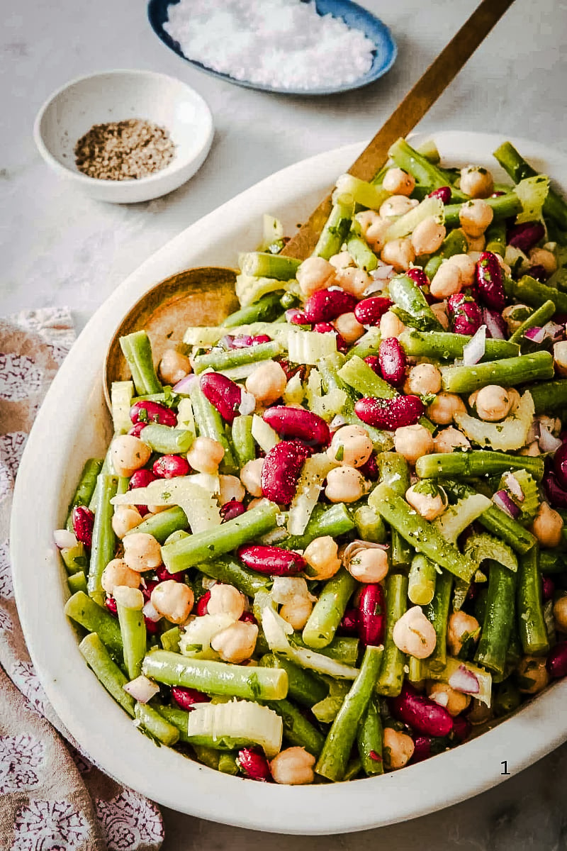 3 Bean Salad with green beans, kidney beans, chickpeas, celery, and red onion in a white serving bowl with a light vinaigrette