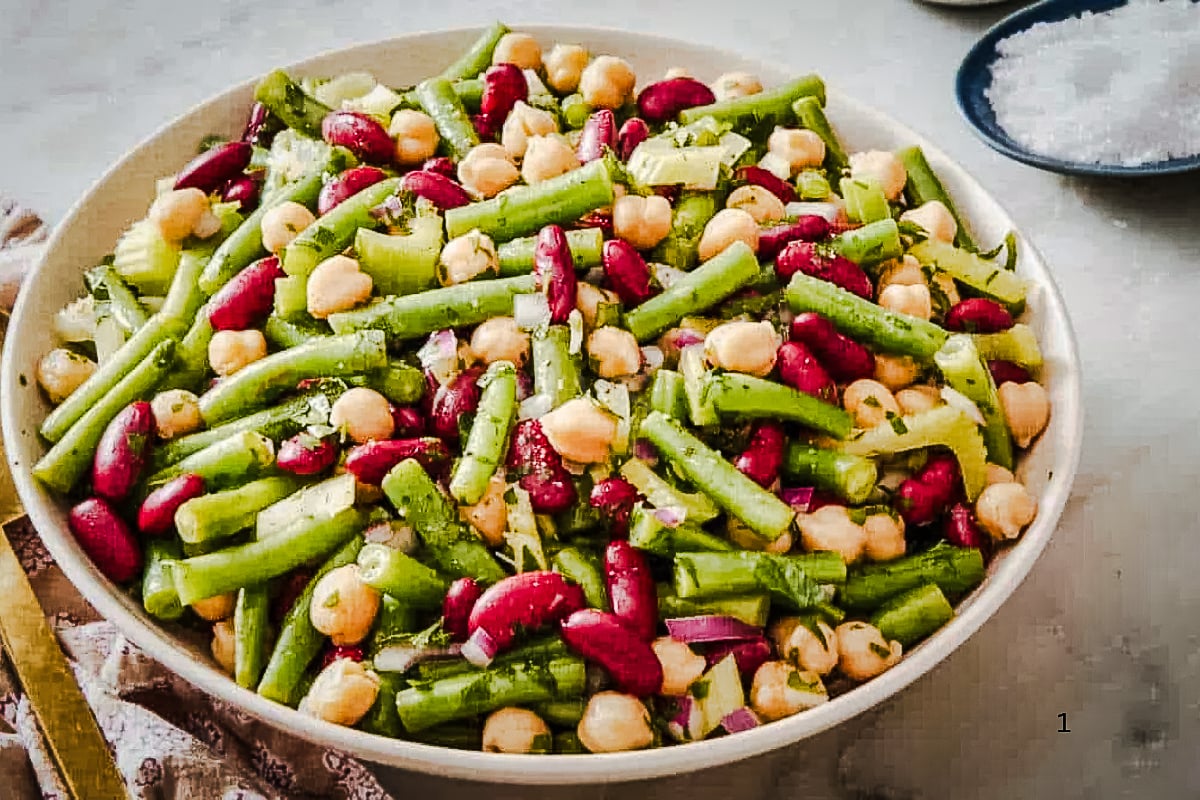 Fresh 3 Bean Salad with green beans, kidney beans, chickpeas, celery, red onion, and herbs in a large serving bowl