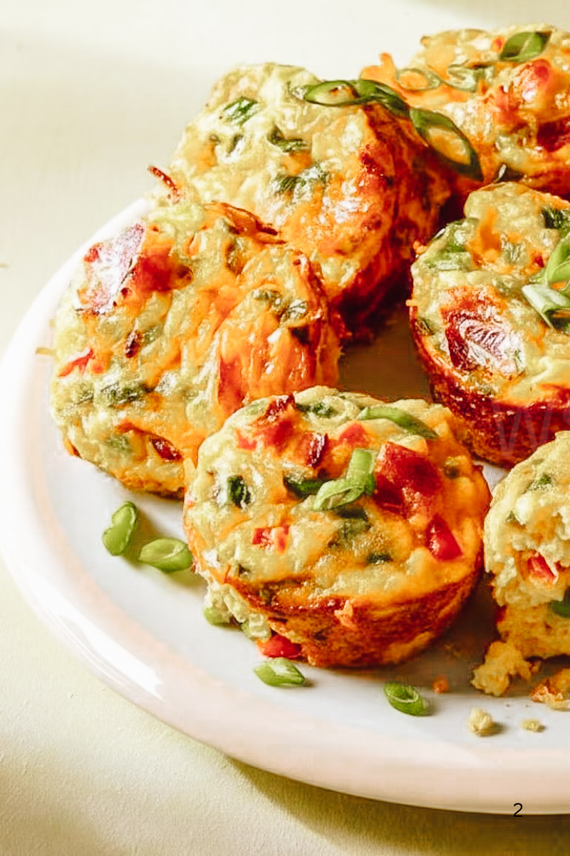 Close-up of high protein air fryer egg muffins with cottage cheese, red bell pepper, and green onions on a white plate, showing their fluffy texture and golden tops.