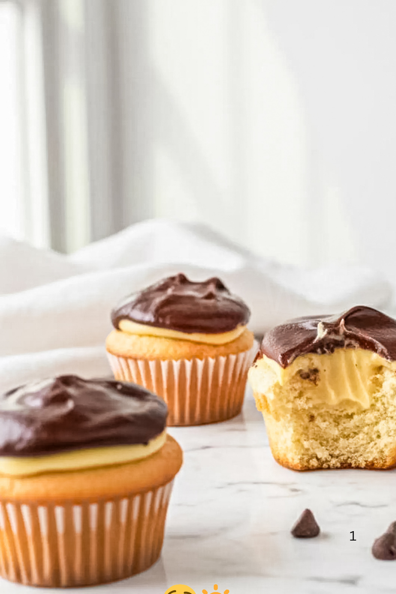 Boston Cream Cupcakes with vanilla pastry cream filling and glossy chocolate topping, including one cupcake cut open to show the creamy center inside.