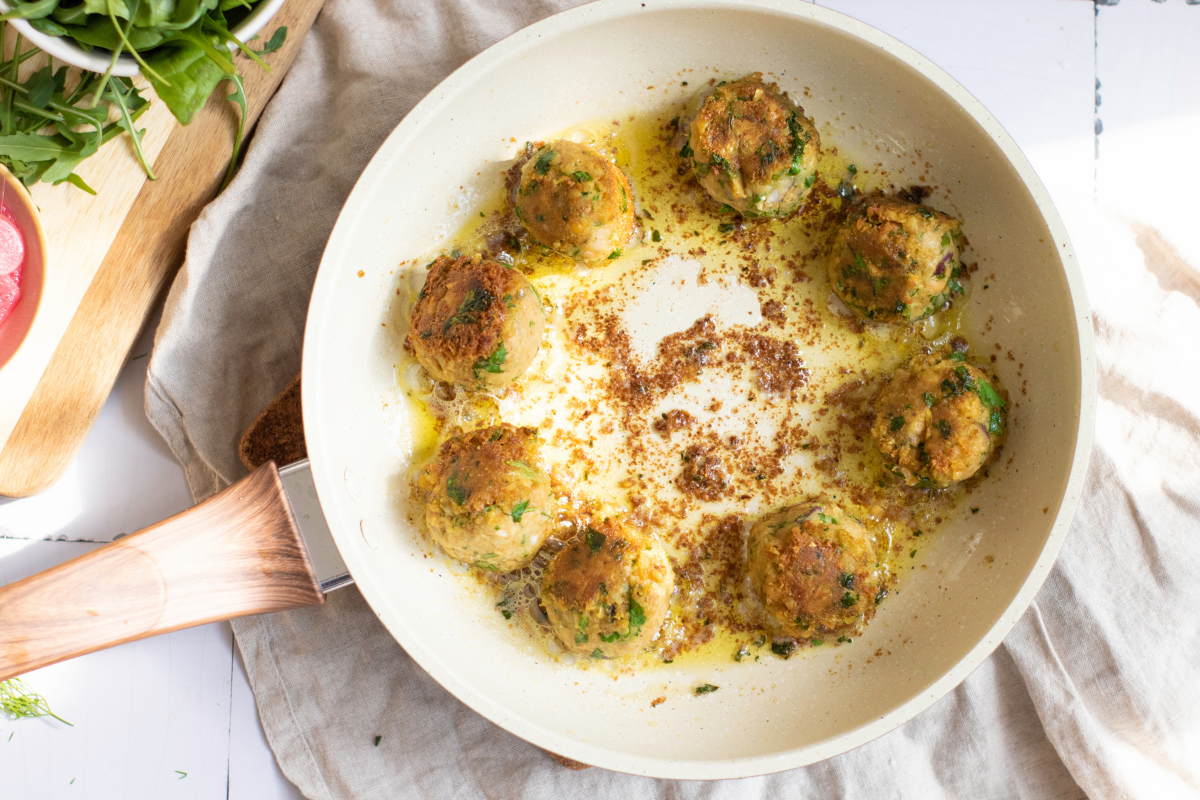 Golden crispy falafel balls draining on a paper towel after pan frying for homemade falafel wraps.