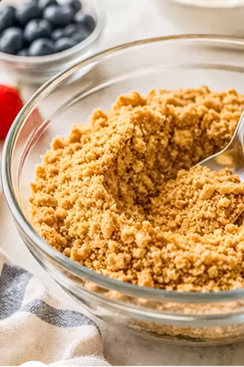 Graham cracker crumb mixture in a glass bowl for making mini no-bake cheesecake crusts.