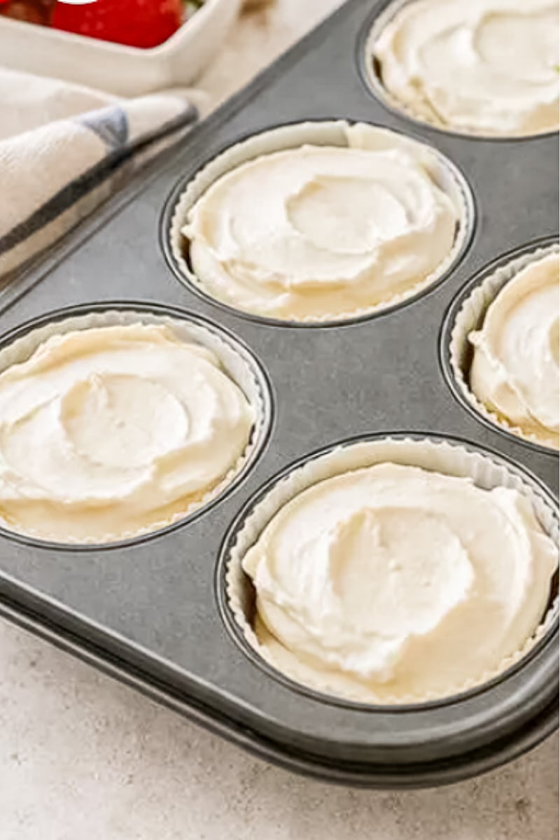 Mini no-bake cheesecakes filled with creamy vanilla cheesecake filling inside cupcake liners in a muffin tin.