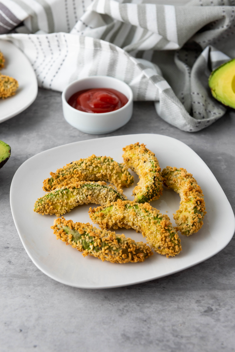 Crispy vegan air fryer avocado fries served on a plate with dipping sauce
