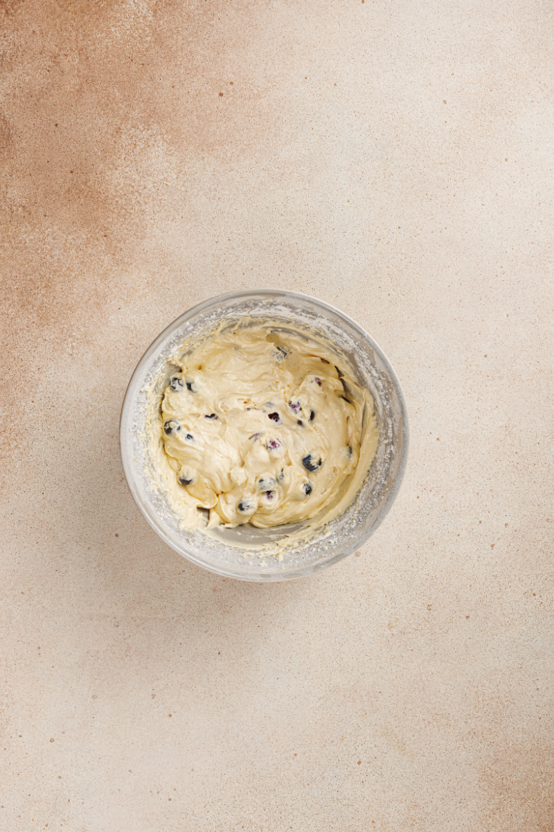 Thick lemon cake batter with fresh blueberries folded in before baking.