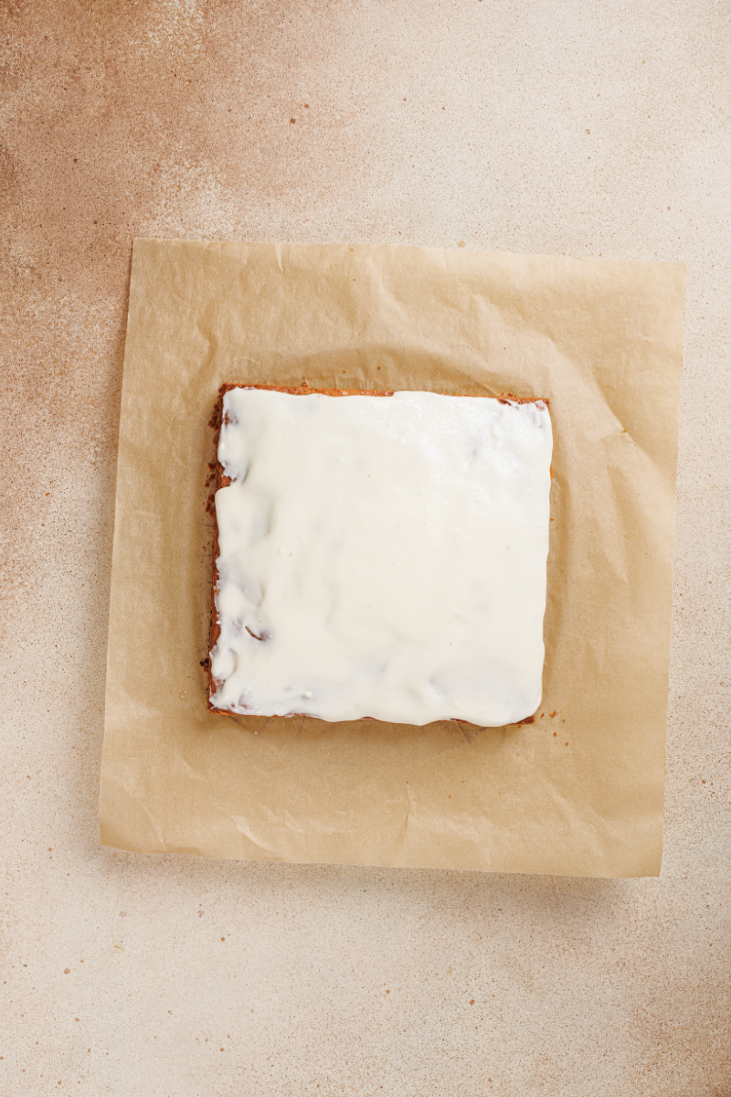Lemon blueberry cake covered with smooth cream cheese frosting before slicing into squares.