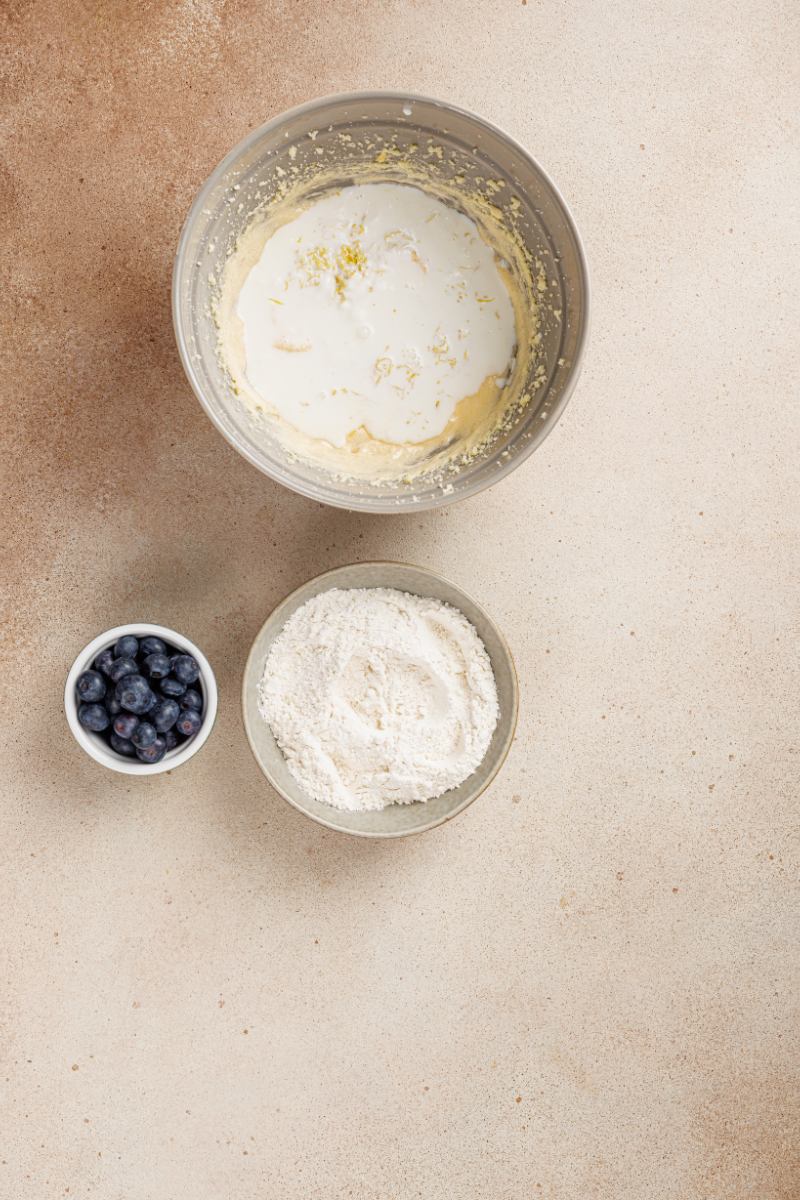 Buttermilk poured into lemon cake batter with lemon zest before adding flour and blueberries.