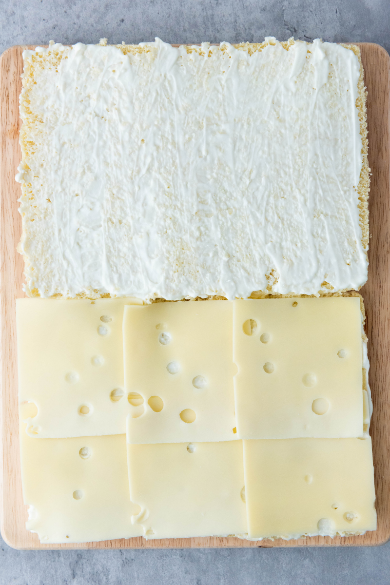 Swiss cheese slices layered over slider buns for ham and cheese sliders.