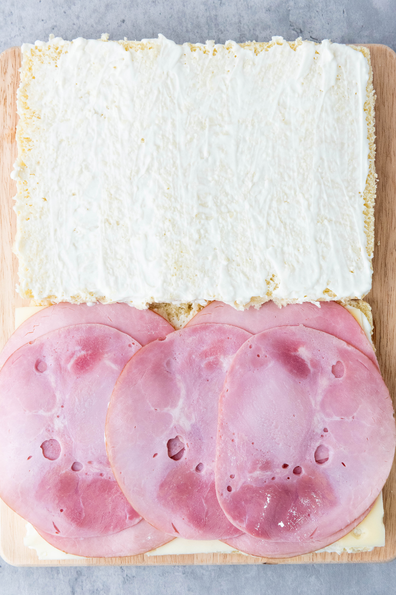 Thin slices of ham layered over Swiss cheese on slider buns.