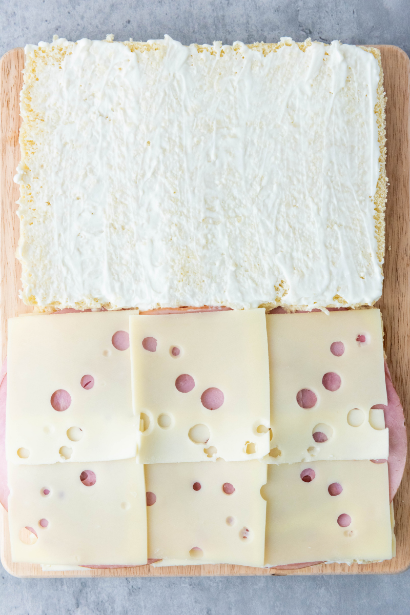 Swiss cheese layered over sliced ham for baked ham and cheese sliders.