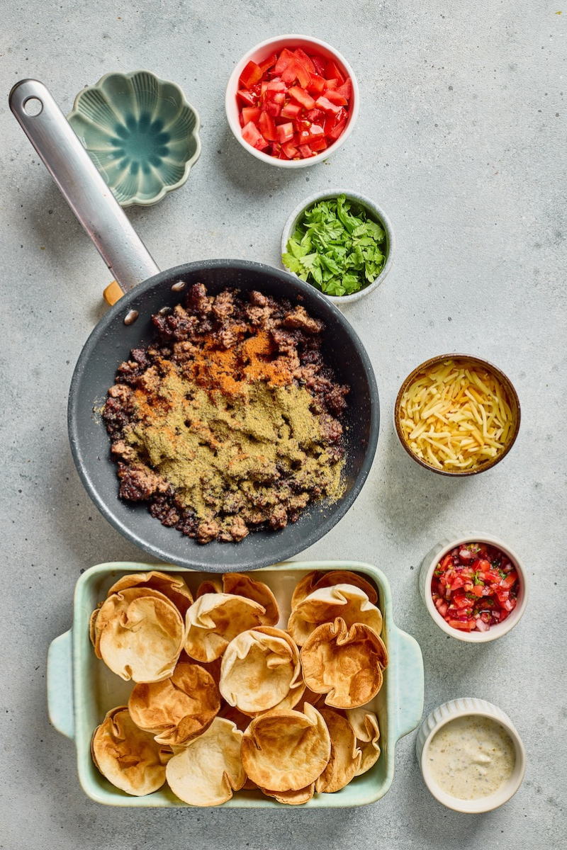 Taco seasoning and ranch seasoning sprinkled over browned ground beef in a skillet while preparing the savory filling for crispy taco ranch bites.