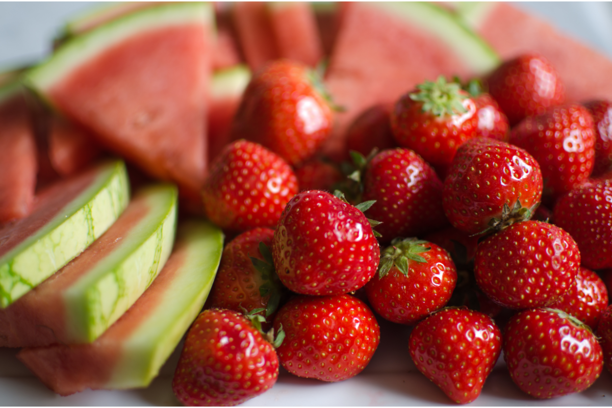 Fresh strawberries and sliced watermelon arranged together, showing the main fruit ingredients for homemade strawberry watermelon popsicles and refreshing summer frozen treats.