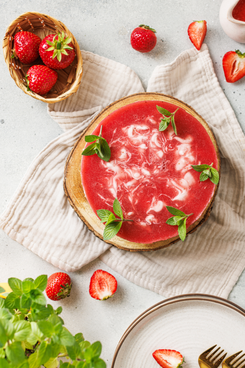 Finished no-bake strawberry cheesecake with strawberry swirl topping, fresh mint, and strawberries.