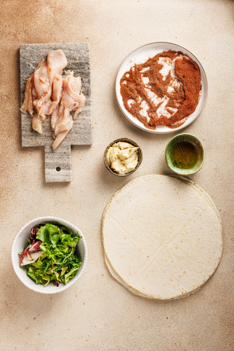 Chicken strips being coated with Moroccan spice blend including paprika, cumin and cinnamon