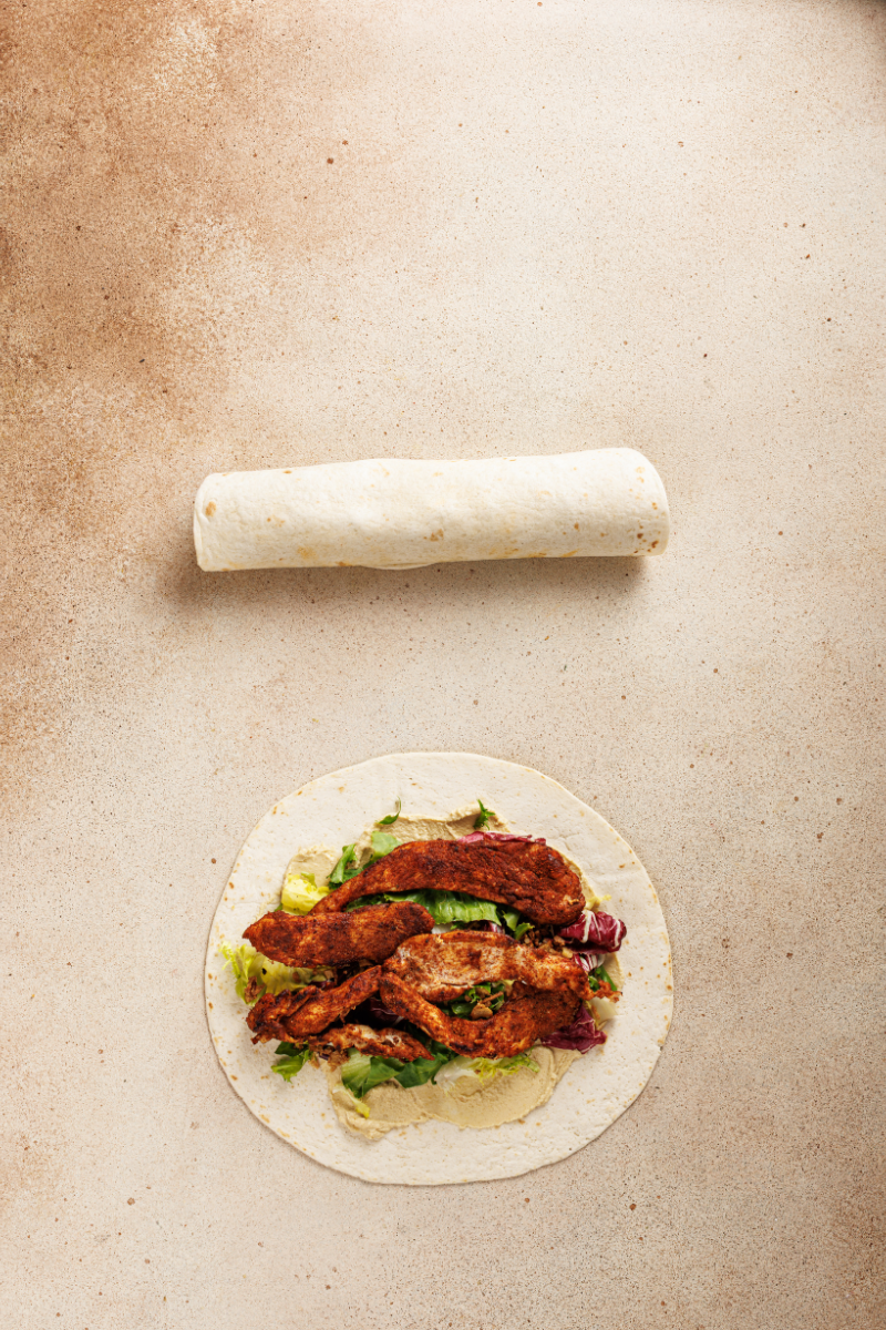 Tortilla rolled tightly around Moroccan chicken and greens filling