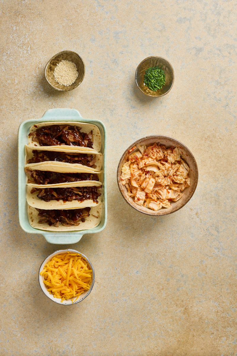 Korean pulled pork tacos drizzled with barbecue sauce before adding quick kimchi and cheese.

