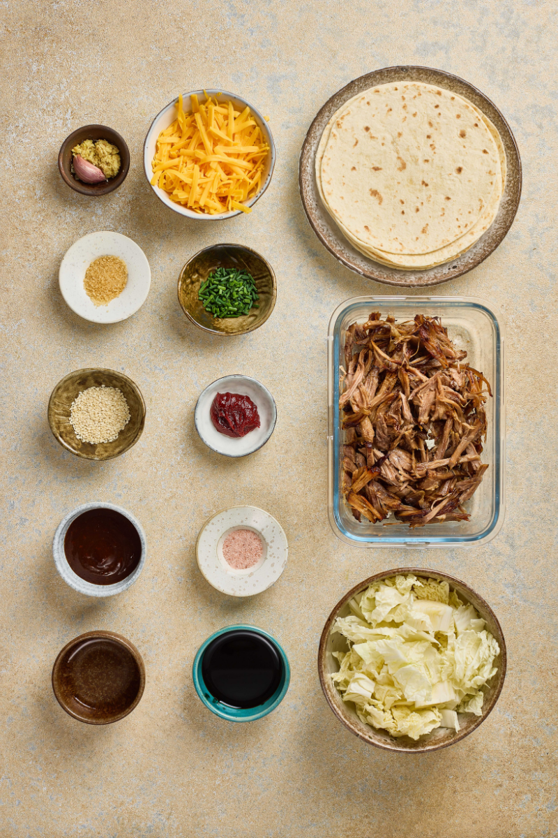 These Korean BBQ Pulled Pork Tacos with Quick Kimchi are smoky, tangy, cheesy, and just spicy enough to wake up taco night. Tender pulled pork is warmed with barbecue sauce and tucked into soft tortillas. Quick napa cabbage kimchi adds crunch and brightness. Melted cheddar cheese, green onions, and sesame seeds bring everything together.