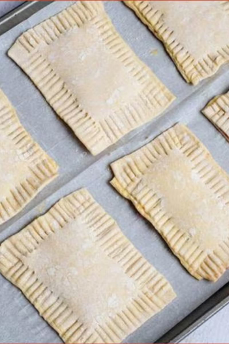 Raspberry puff pastry turnovers sealed with fork-crimped edges and ready for baking