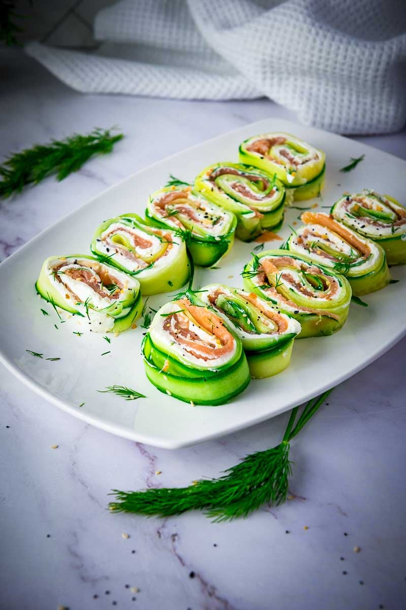 Everything Bagel Cucumber Rolls with cream cheese and smoked salmon arranged on a serving platter with fresh dill and everything bagel seasoning.