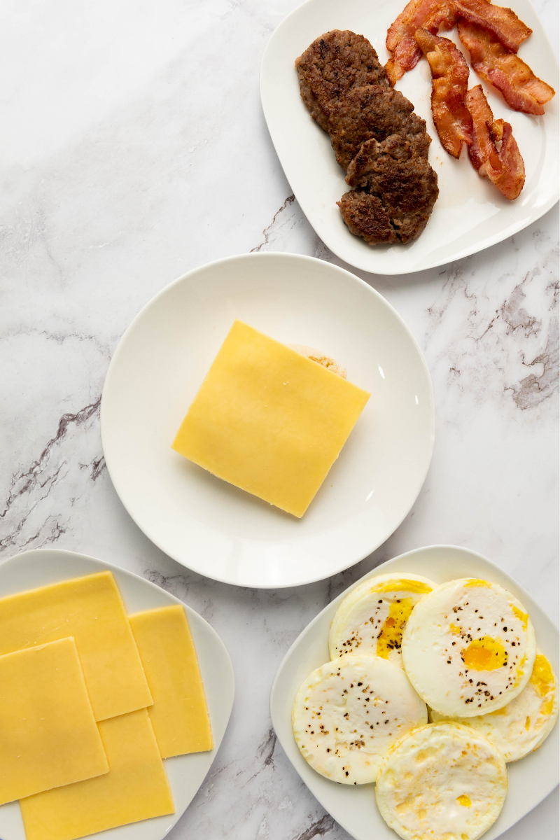 Slice of cheese placed on an English muffin for a sausage breakfast sandwich.